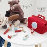 Collection of items including a plush bear, a red bag, and various small objects on a white surface.