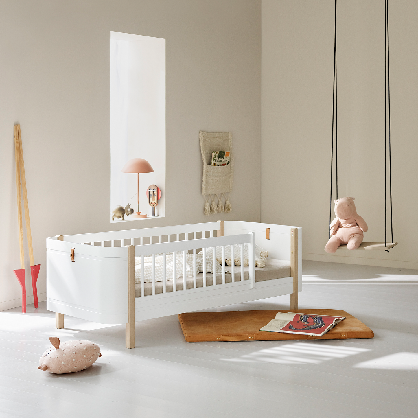 Children's room with a white crib, wooden toys, and a swing.