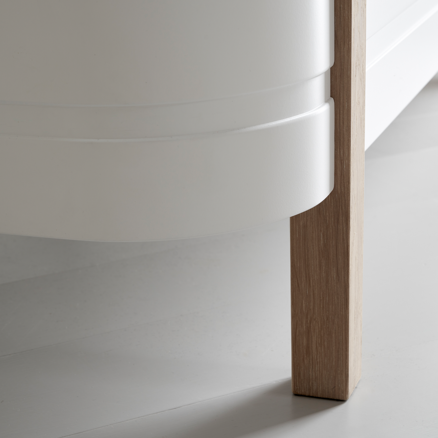 Close-up of a wooden bed frame corner with white mattress
