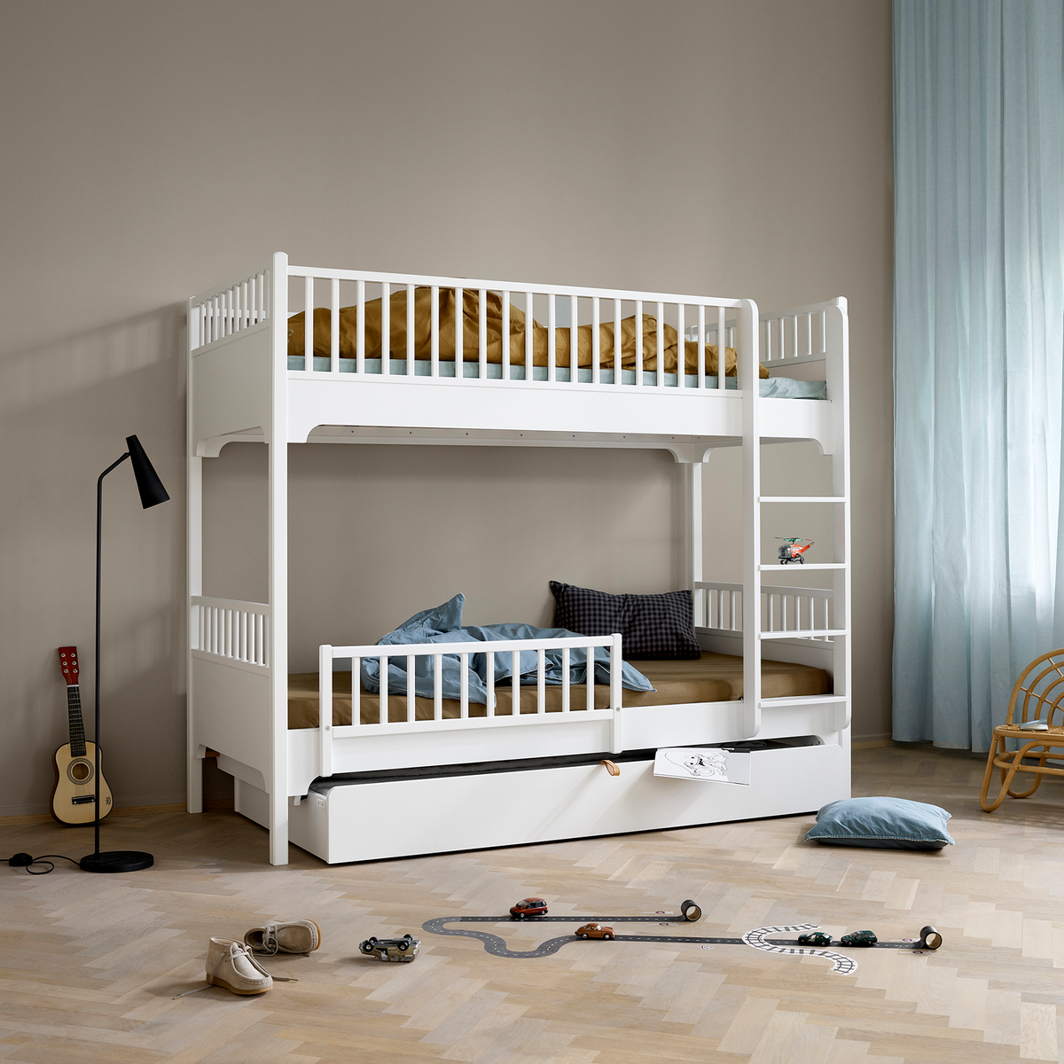 White bunk bed with pull-out trundle in a room with toys on the floor.