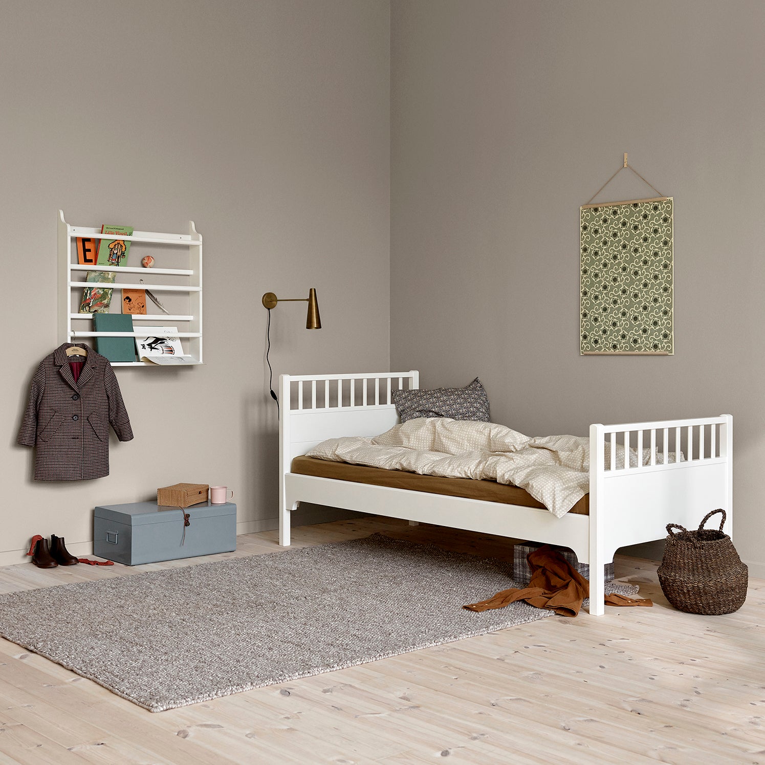 Children's bedroom with a white bed, gray rug, and wall decorations.