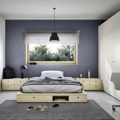 A modern bedroom featuring a light wood platform bed with a gray and white bedding set, set against a dark slate blue-gray accent wall. The room includes a matching light wood nightstand, a large white wardrobe, a gray rug, and a black pendant light.