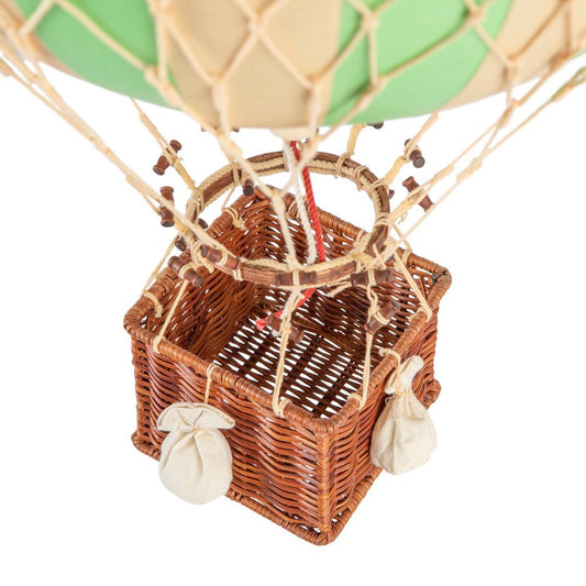 Wicker basket of a hot air balloon with a green balloon on a white background