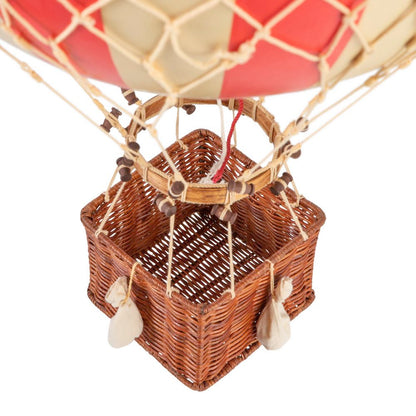 Close-up of a wicker basket attached to a hot air balloon with a red envelope.