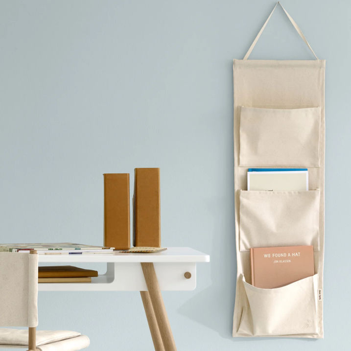 Beige wall-mounted organizer with books on a light blue wall
