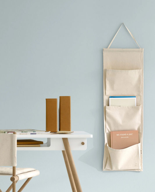 Beige wall-mounted organizer with books on a light blue wall