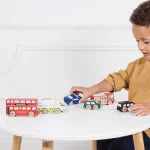 Child playing with toy cars on a white table
