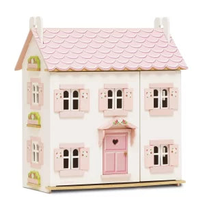 Small wooden dollhouse with pink roof and door on a white background