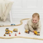Child playing with toy train set on a white floor