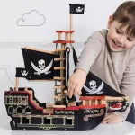 Child playing with a toy pirate ship set against a plain background