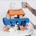 Small doghouse and figurines on a shelf with a person taking a photo.