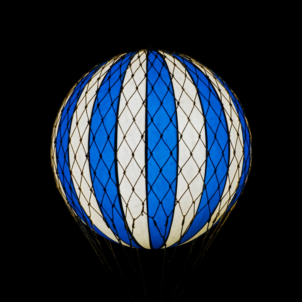 Blue and white striped balloon against a black background