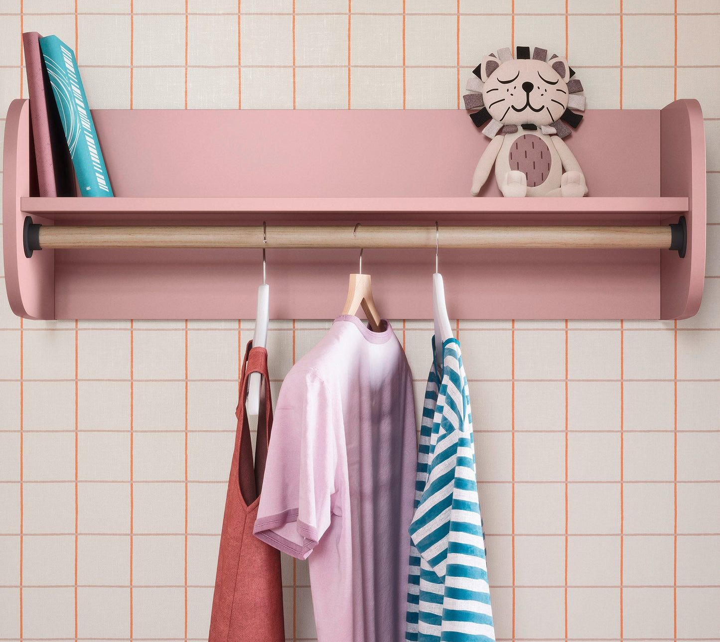 Pink wall-mounted rack with clothes and a toy on a tiled wall background