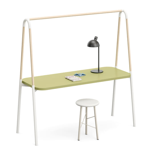 A minimalist desk with a light sage green top, white metal legs, and natural wood A-frame supports, accompanied by a white stool and a black desk lamp on a clean white background.