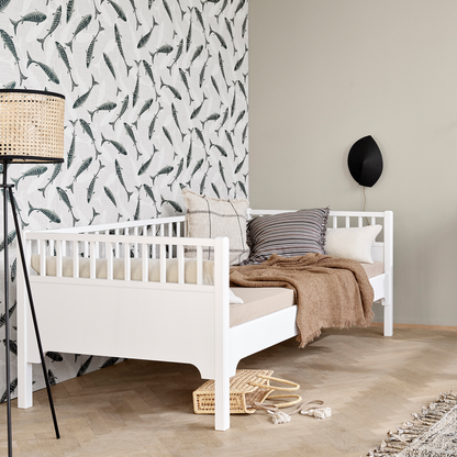 Children's bedroom with a white crib, patterned wallpaper, and wooden floor.