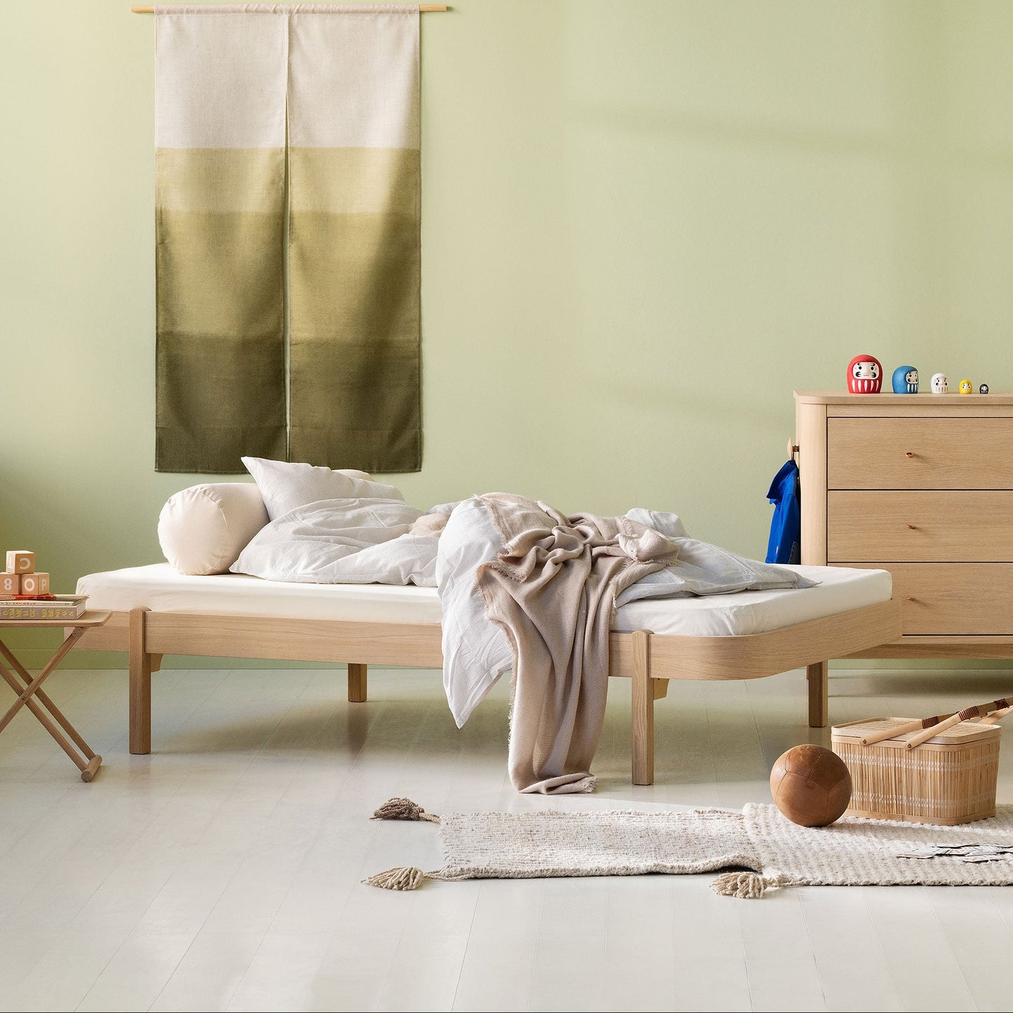 Minimalist bedroom with a bed, dresser, and wall art.