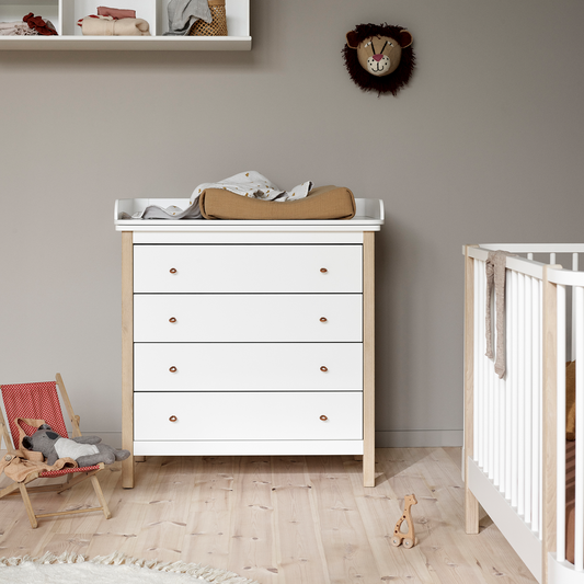Nursery with white dresser, crib, and wall decorations.
