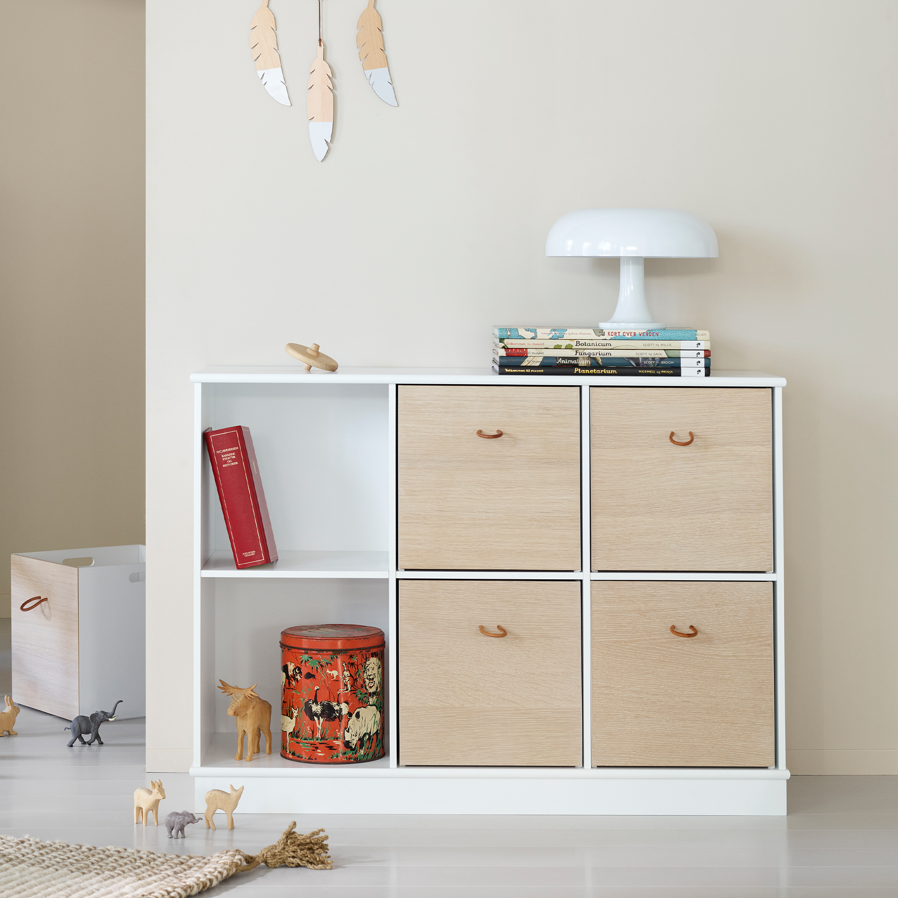 White shelf with wooden drawers and decorative items against a plain wall.