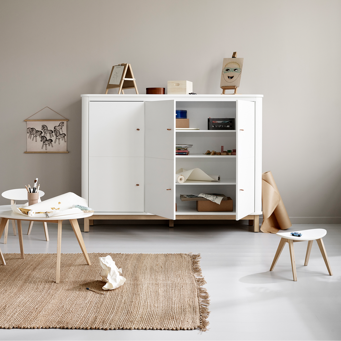 White storage unit in a minimalistic room with a beige rug and small table.