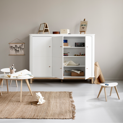 White storage unit in a minimalistic room with a beige rug and small table.