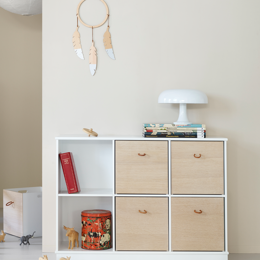 White shelf with wooden drawers and decorative items against a plain wall.