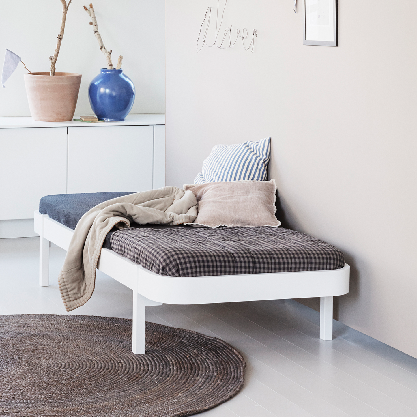 dAY bED with cushions and a blanket in a room with a plant and wall art.