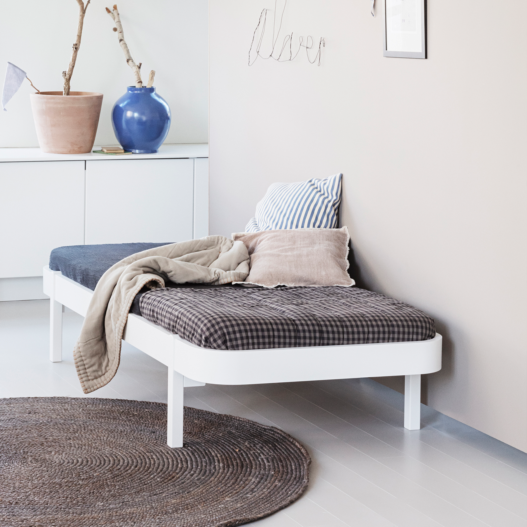 dAY bED with cushions and a blanket in a room with a plant and wall art.
