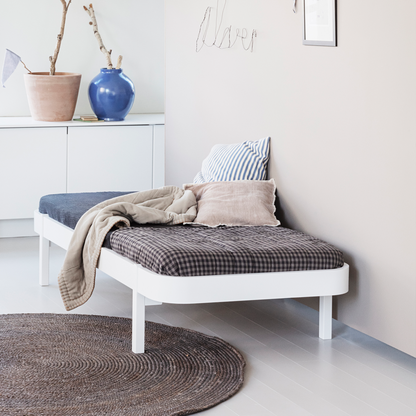 dAY bED with cushions and a blanket in a room with a plant and wall art.