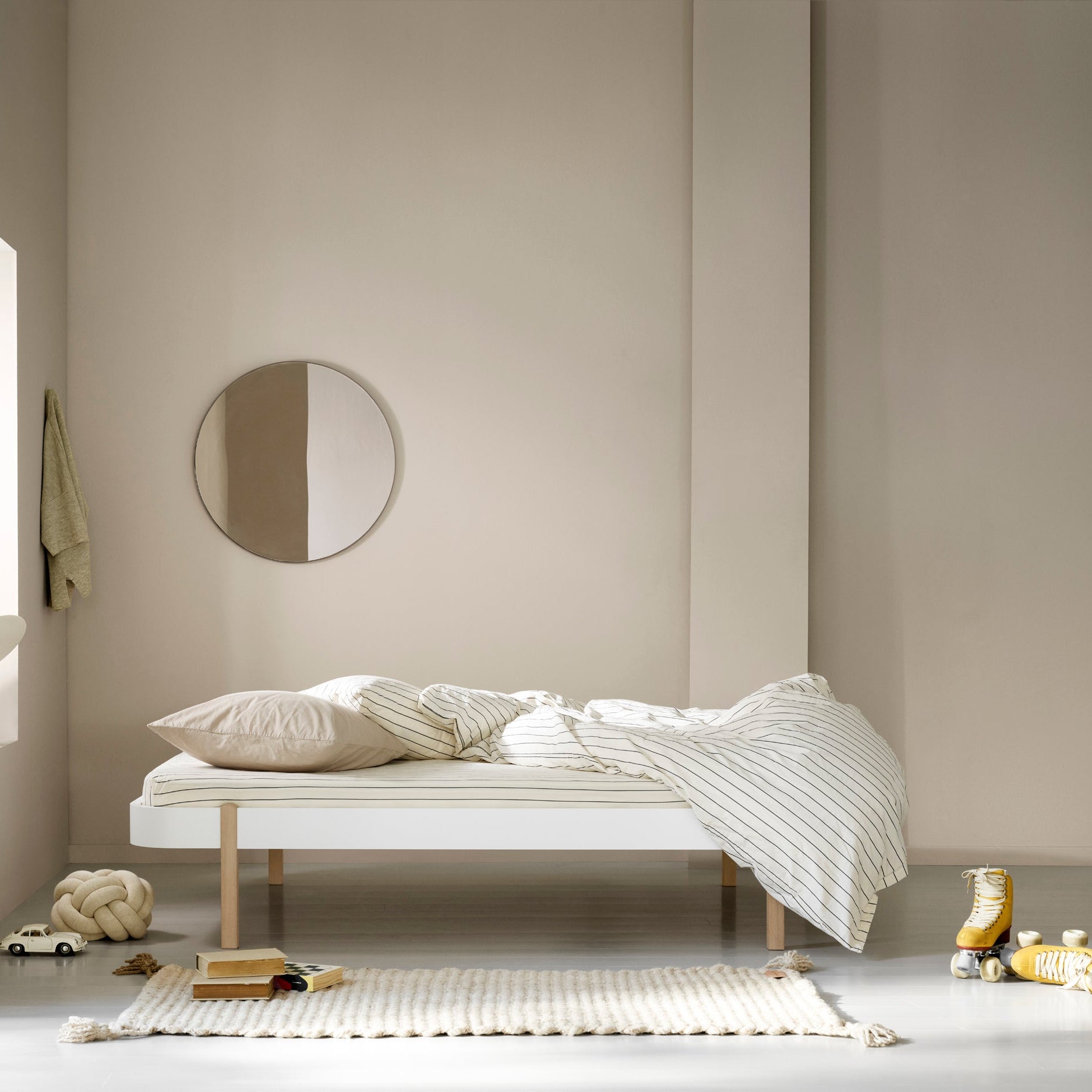 Minimalist bedroom with a bed, round mirror, and decorative items.