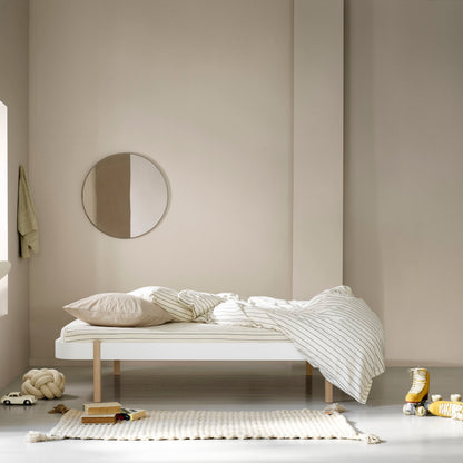 Minimalist bedroom with a bed, round mirror, and decorative items.