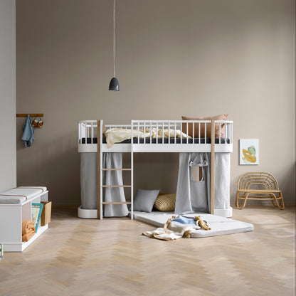 Children's room with a white loft bed, storage unit, and toys on a wooden floor.