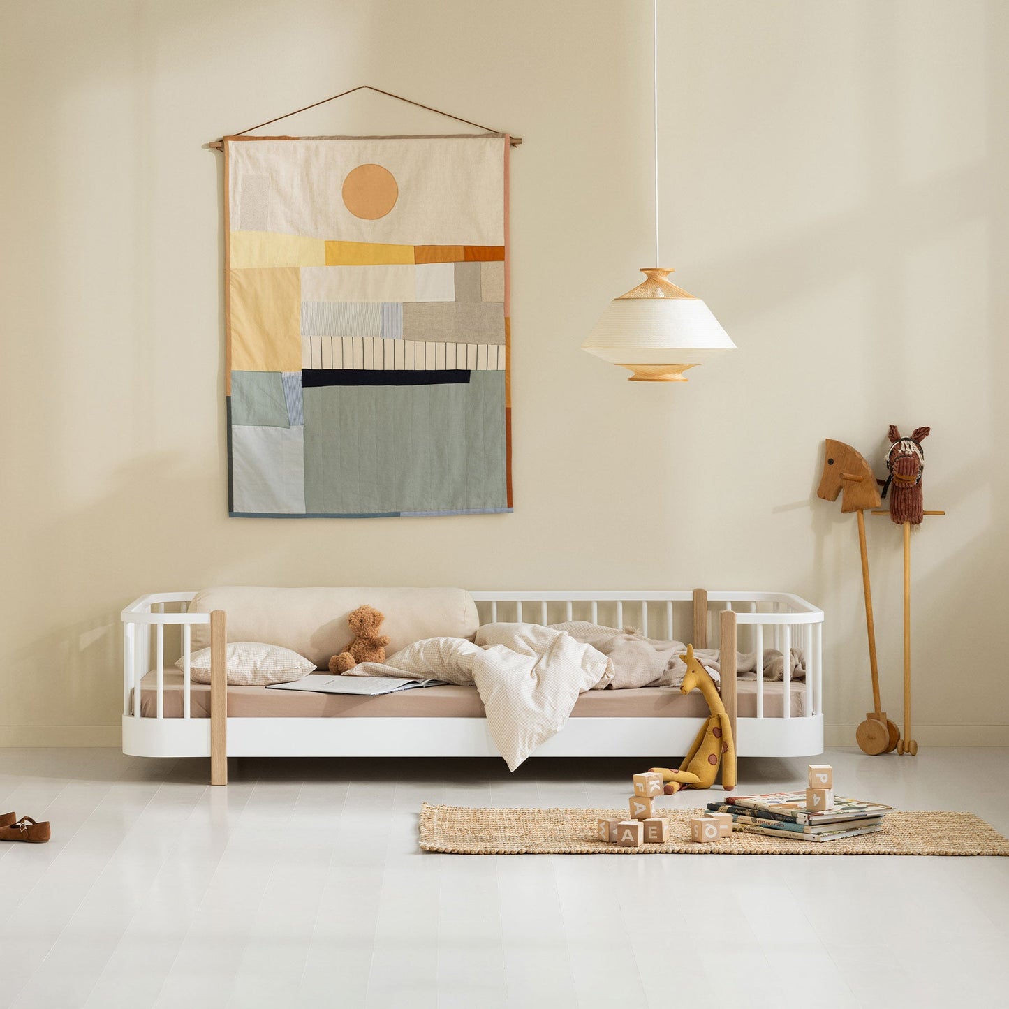 Children's room with a white crib, colorful wall hanging, and wooden toys.