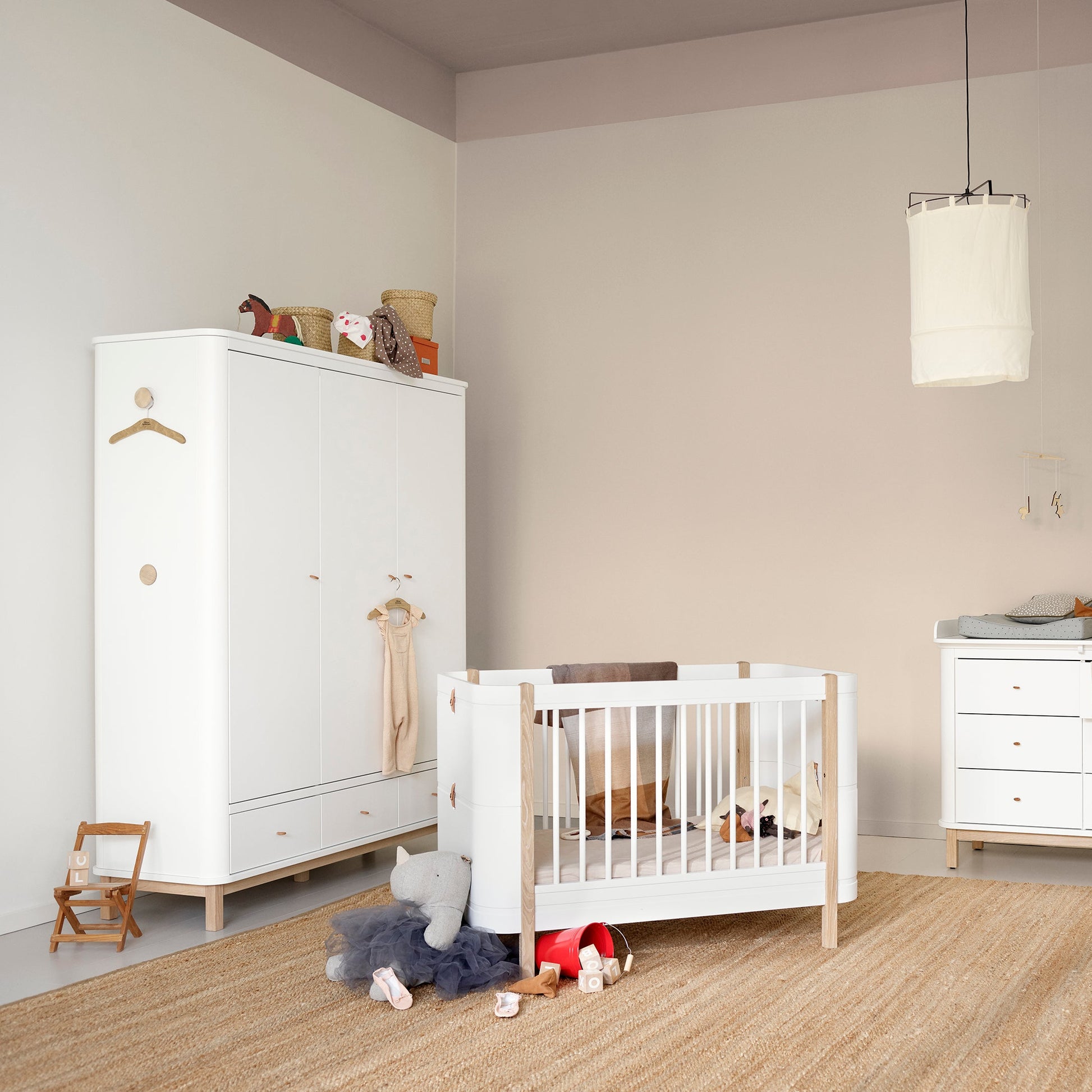 Nursery room with white crib, dresser, and wardrobe.