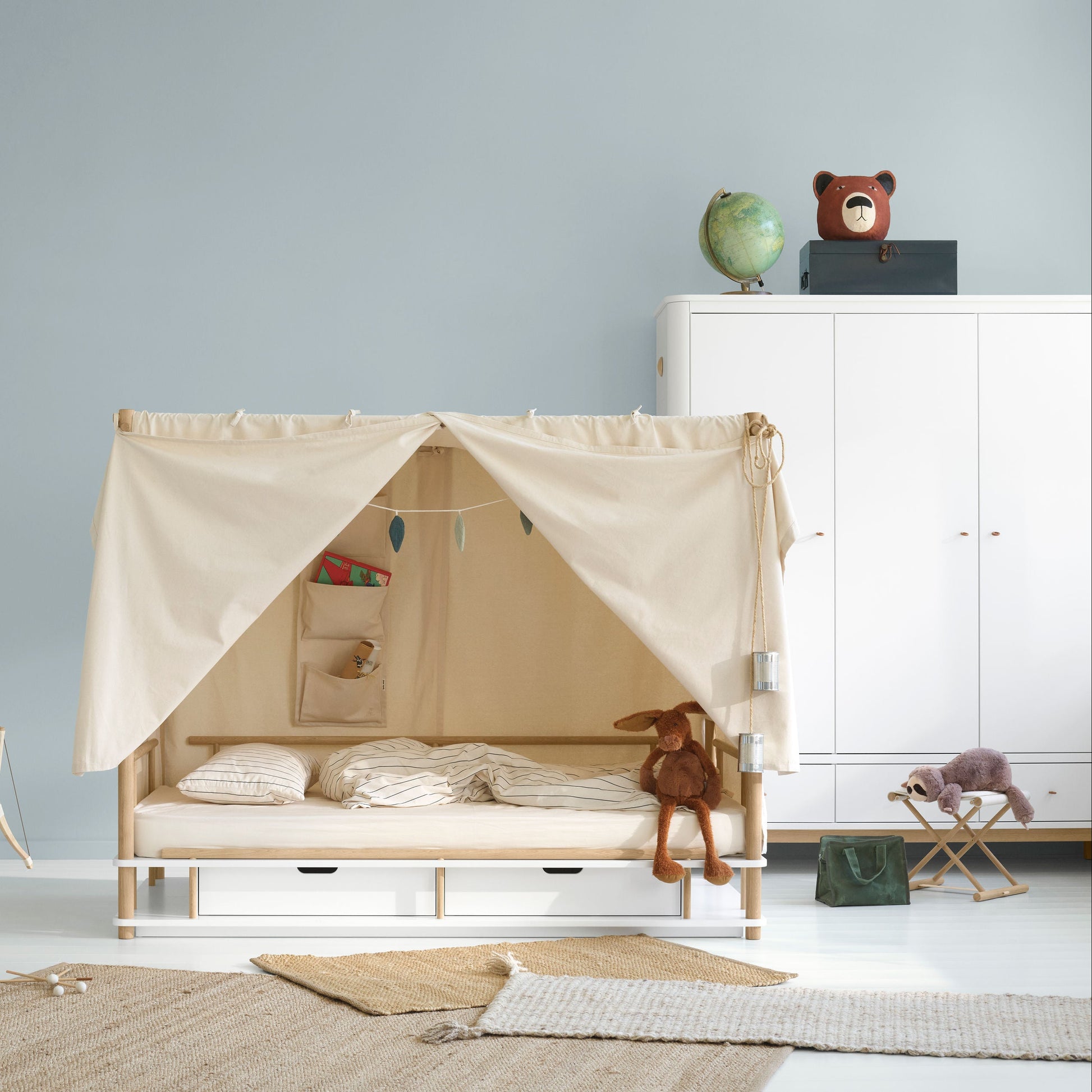 Children's room with a wooden bed with a canopy, toys, and furniture.