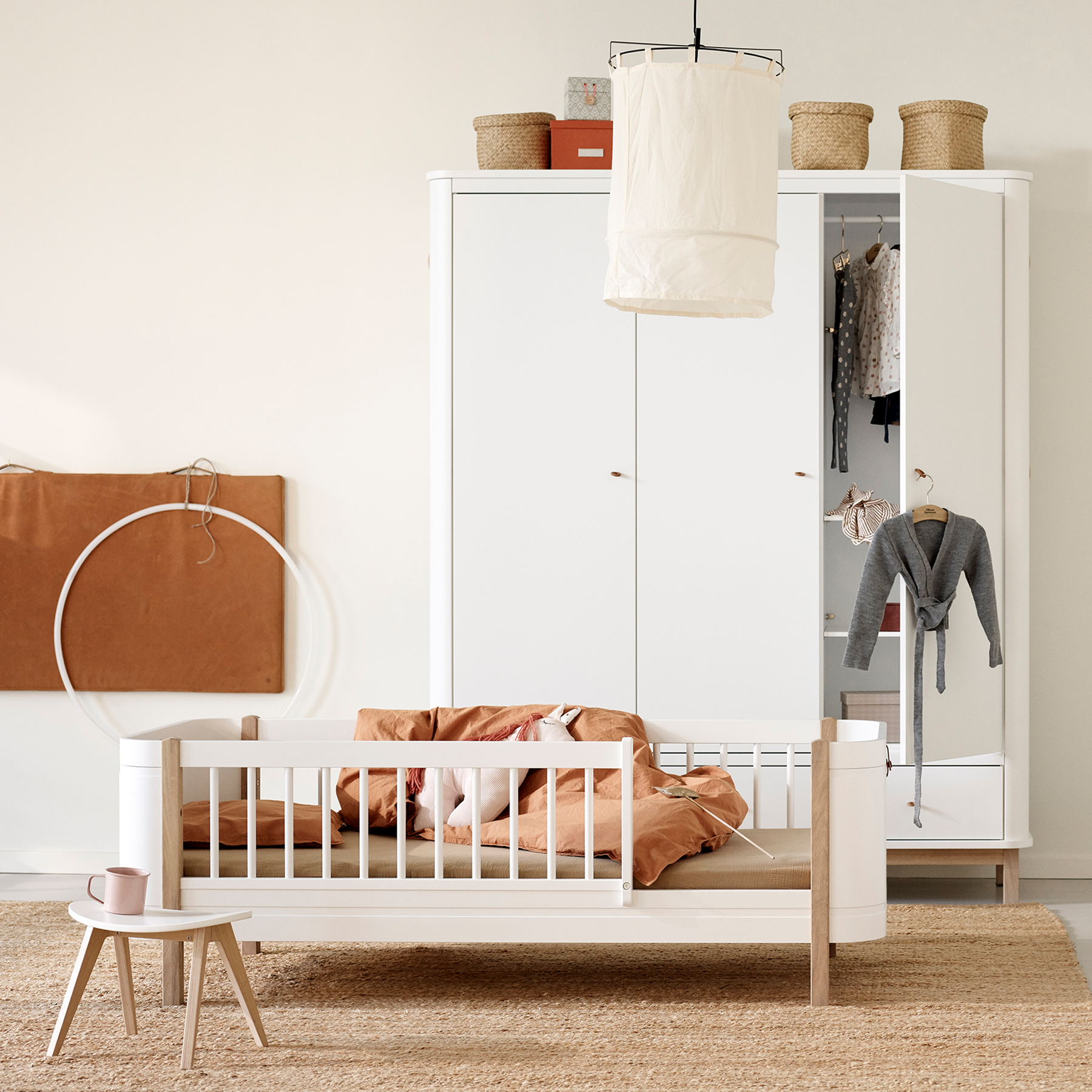 Children's room with a crib, wardrobe, and hanging clothes