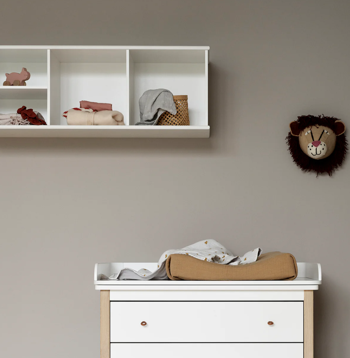 Nursery with a changing table, shelves, and decorative items on a beige wall.
