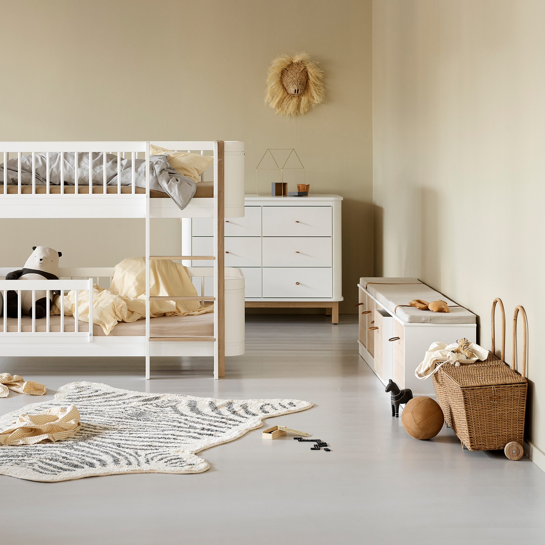 Nursery room with white crib, dresser, and toys on a light gray floor.