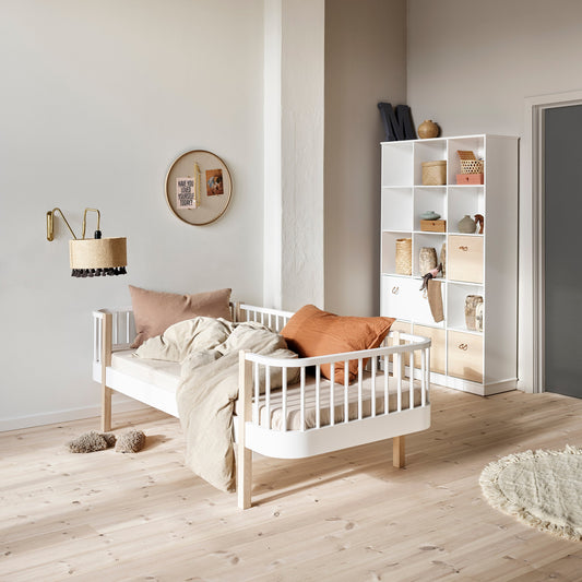 Children's room with a white crib, bookshelf, and decorative items.