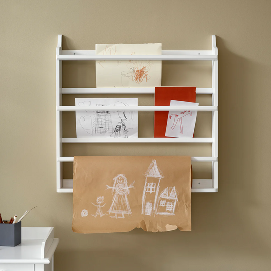 White wall-mounted rack with children's drawings on a beige wall