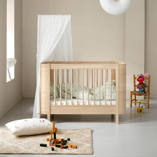 Nursery room with a wooden crib, toys, and a hanging lamp.