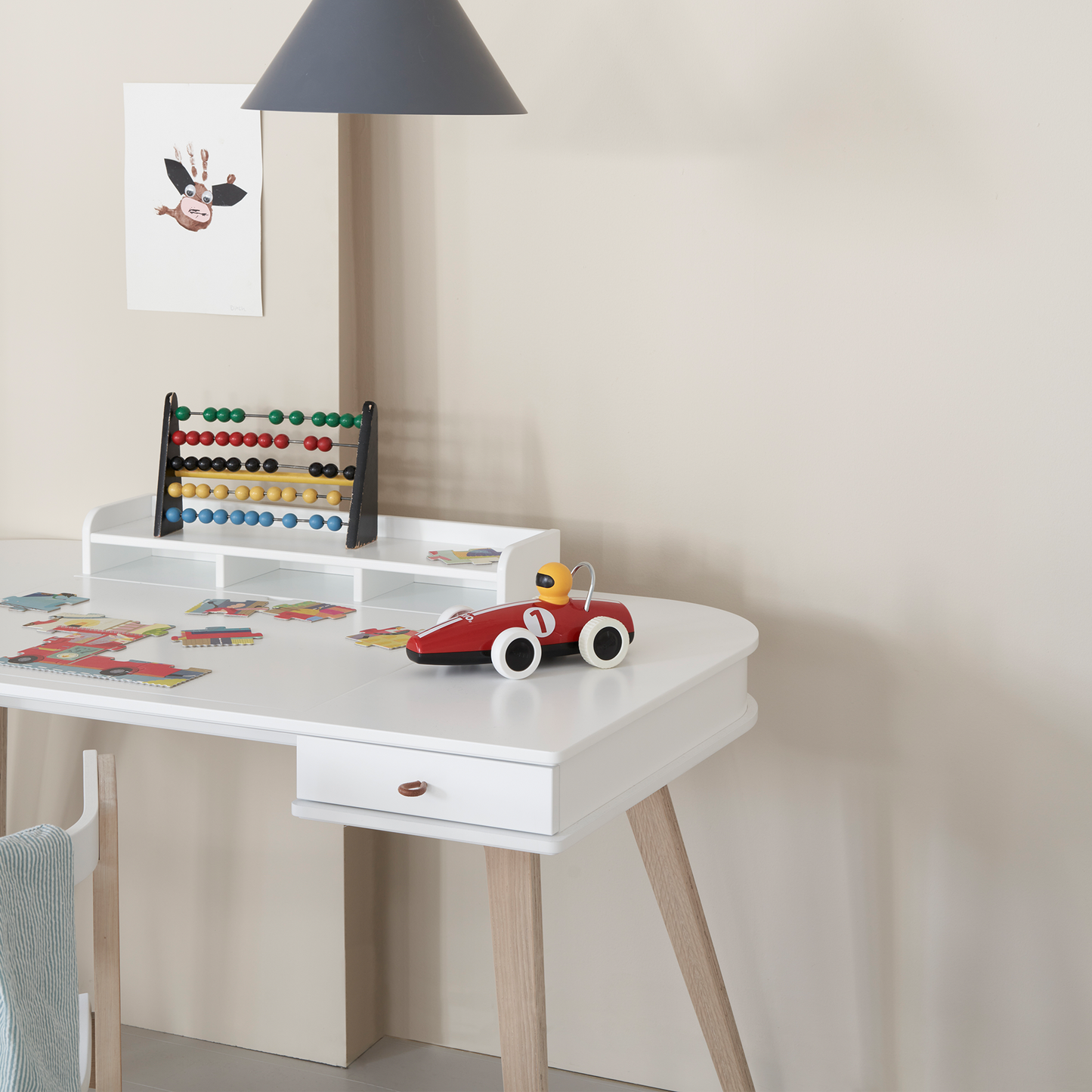 White children's desk with toys and a lamp in a room setting