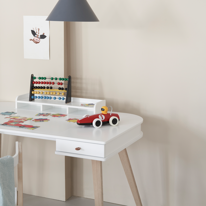 White children's desk with toys and a lamp in a room setting