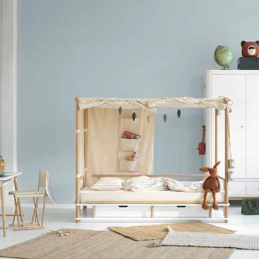 Children's room with a wooden crib, toys, and furniture against a light blue wall.