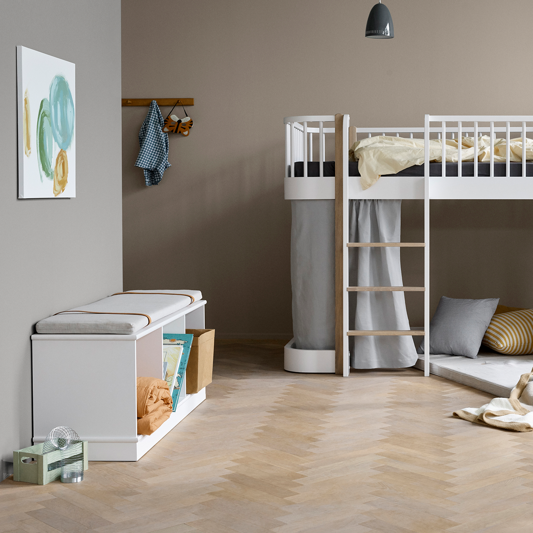 Children's room with a loft bed, storage bench, and toys on a wooden floor.