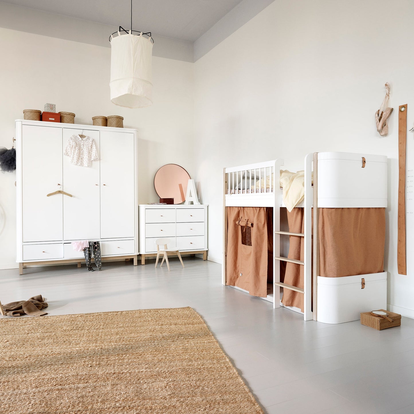 Children's room with white furniture, a bed with brown curtains, and a rug.