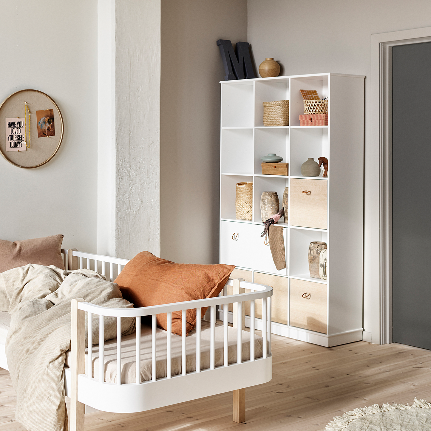 Children's room with a white crib and storage unit.