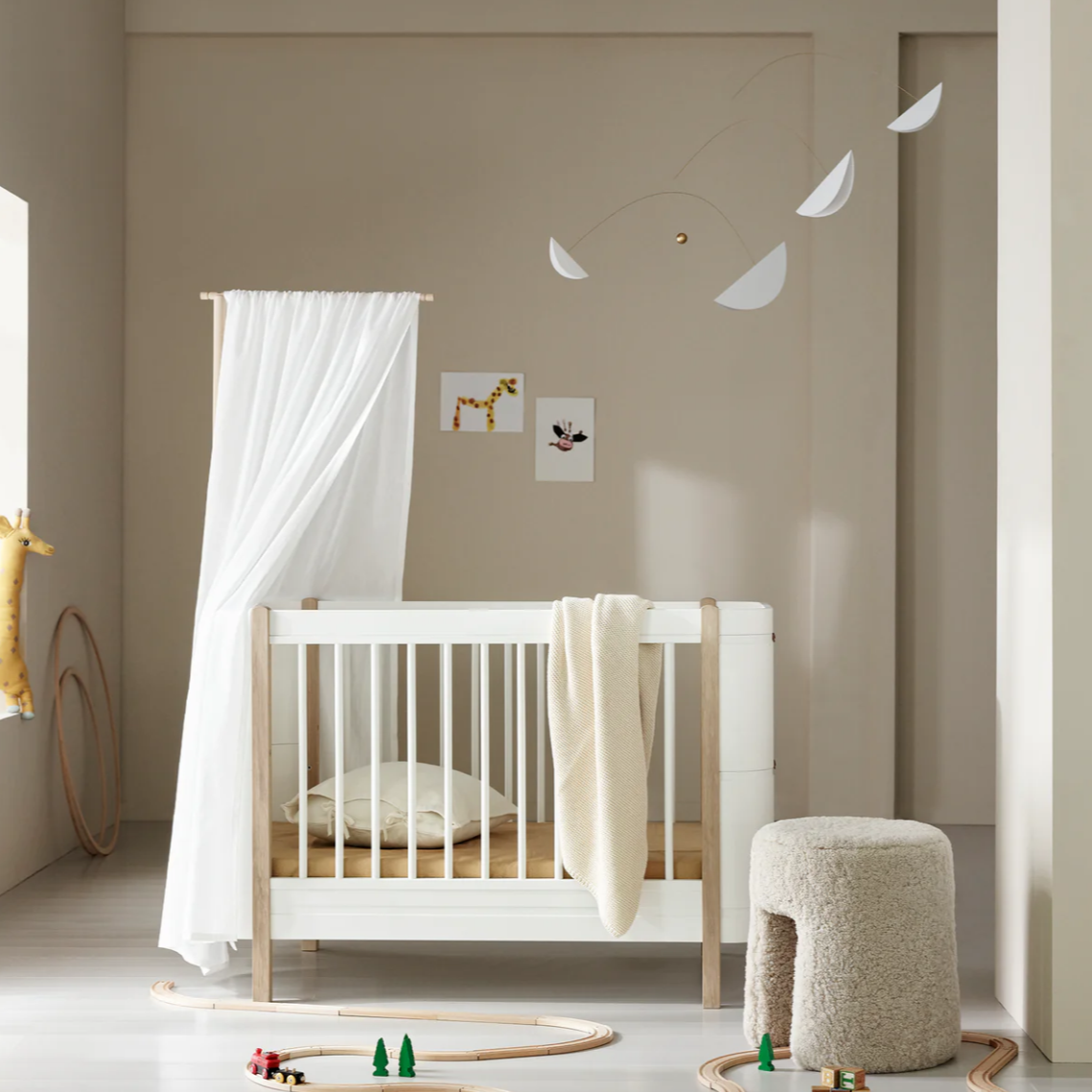 Nursery room with a white crib, decorative elements, and a neutral color scheme.
