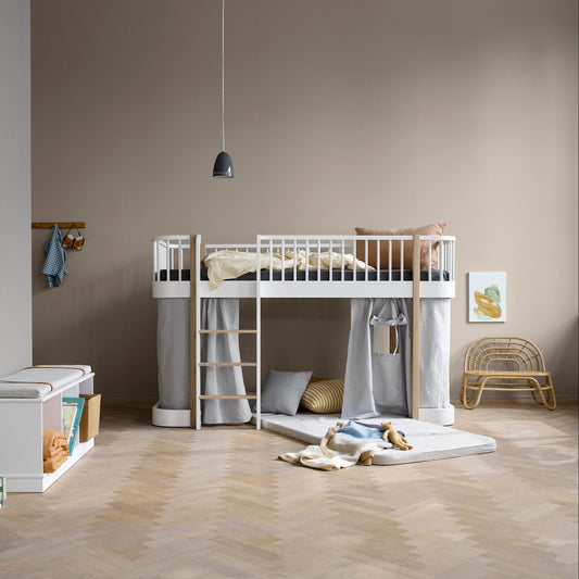 Children's room with a white loft bed, storage unit, and toys on a wooden floor.