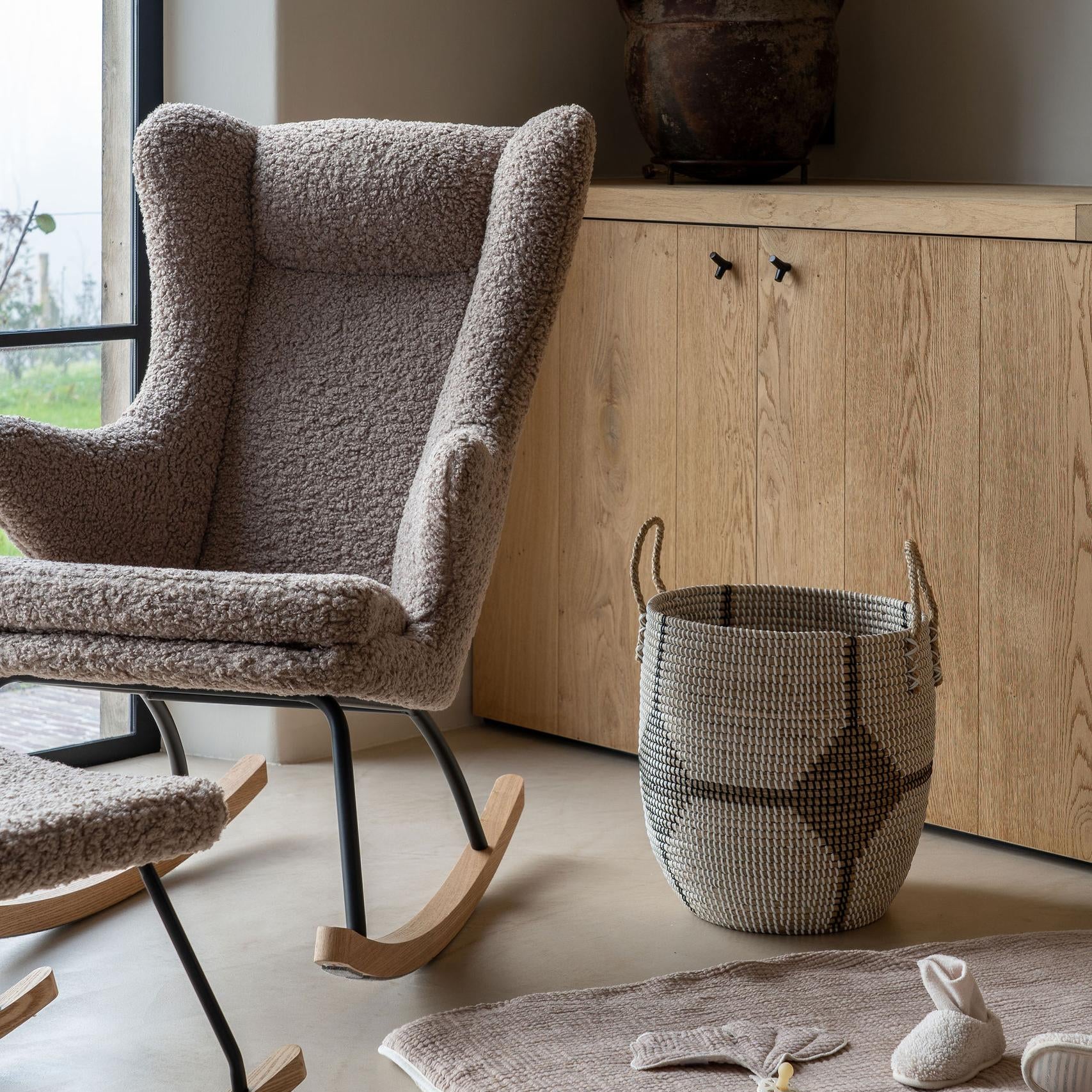 nursing Rocking chair in a room with a wooden cabinet and decorative items.