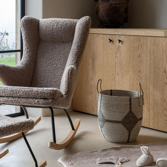 nursing Rocking chair in a room with a wooden cabinet and decorative items.